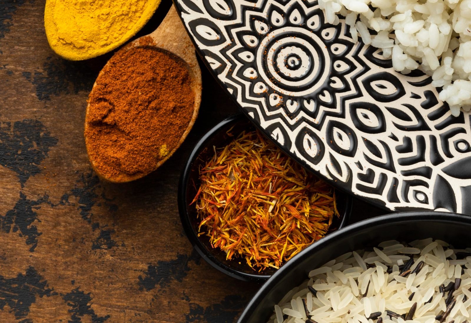 Turmeric, chilli powder and saffron in wooden spoons